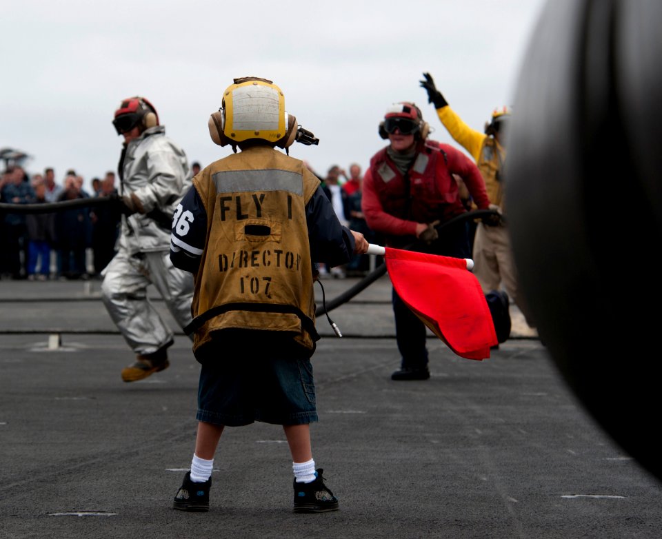 US Navy 110613-N-DR144-100 A sponsored tiger cruise participant waves a flag signifying a class bravo fire as flight deck personnel demonstrate air
