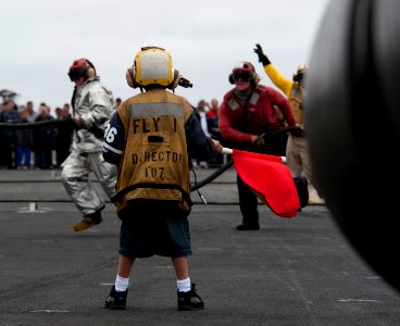 US Navy 110613-N-DR144-100 A sponsored tiger cruise participant waves a flag signifying a class bravo fire as flight deck personnel demonstrate air