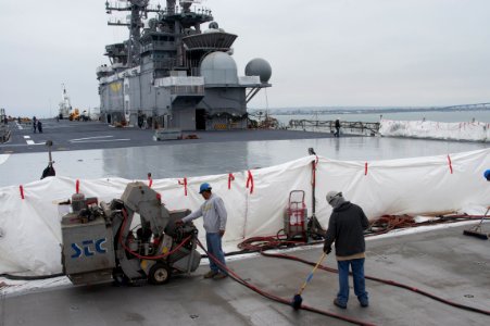 US Navy 110610-N-ZC343-460 Subcontractors for National Steel and Shipbuilding Company (NASSCO) resurface the flight deck of the amphibious assault
