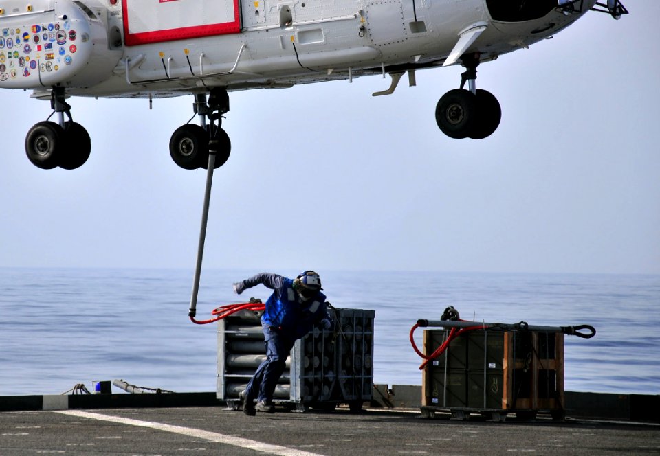 US Navy 110609-N-ZS026-078 Civilian mariner Larcia Rozvel clears the landing area after hooking a crate of ammunition to a 330J Puma helicopter abo
