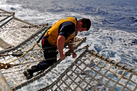 US Navy 110610-N-NR955-005 Boatswain's Mate 2nd Class John Vondrachek tightens turn buckles on flight deck frames aboard the guided-missile destroy