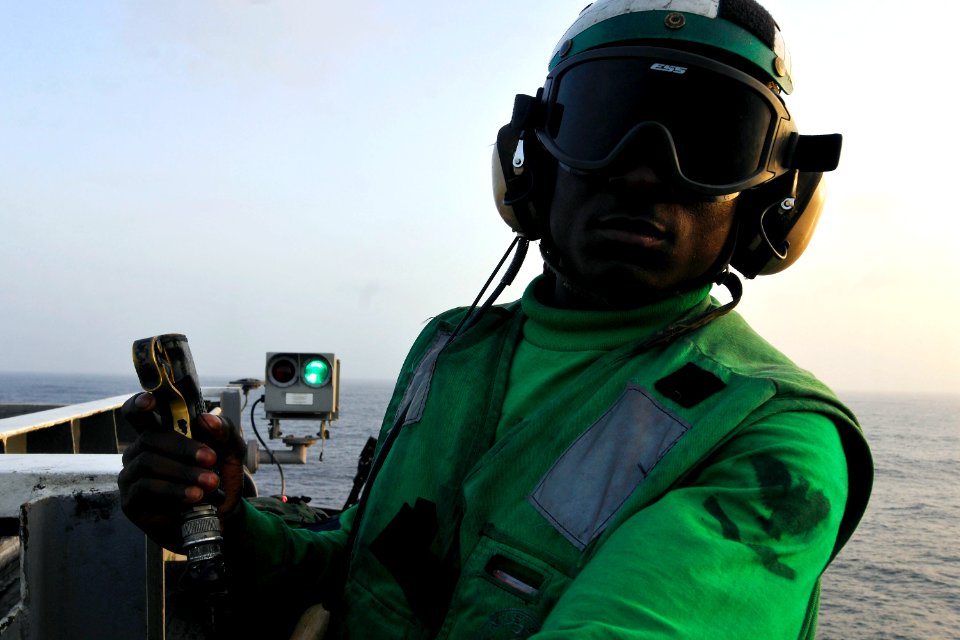 US Navy 110612-N-EE987-507 Aviation Boatswain's Mate Kla Brownell triggers a switch notifying a pilot that the deck is clear to launch from USS Ron