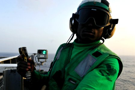 US Navy 110612-N-EE987-507 Aviation Boatswain's Mate Kla Brownell triggers a switch notifying a pilot that the deck is clear to launch from USS Ron