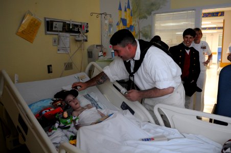 US Navy 110614-N-AD372-046 Sonar Technician (Surface) 1st Class Mark Comeiro assigned to USS Constitution delivers a command ball cap to a child at