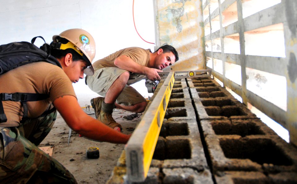 US Navy 110617-N-ZZ999-001 Sapper Benjamin Macpherson of the Australian Army and Steelworker 2nd Class Jessie Majoy level a cinderblock at a GMT en