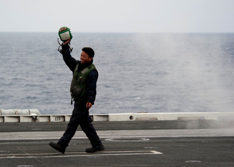 US Navy 110614-N-DR144-830 Aviation Boatswain's Mate (Equipment) 2nd Class Kamal Pereira celebrates the last launch as pilots and aircraft depart U