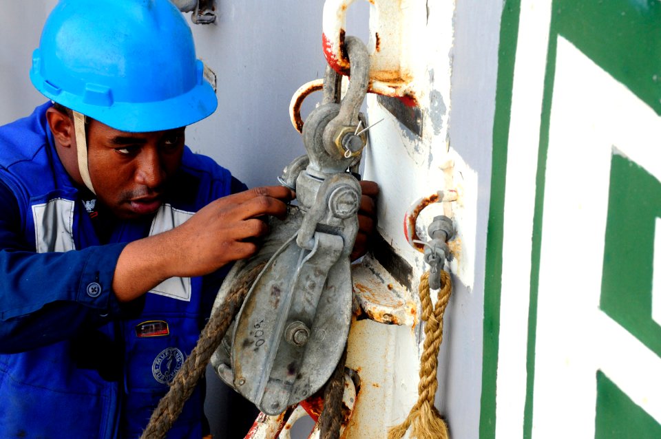 US Navy 110621-N-RC734-067 Boatswain's Mate 2nd Class Sheraul Gumbs runs a line through a pulley aboard USS Comstock (LSD 45)