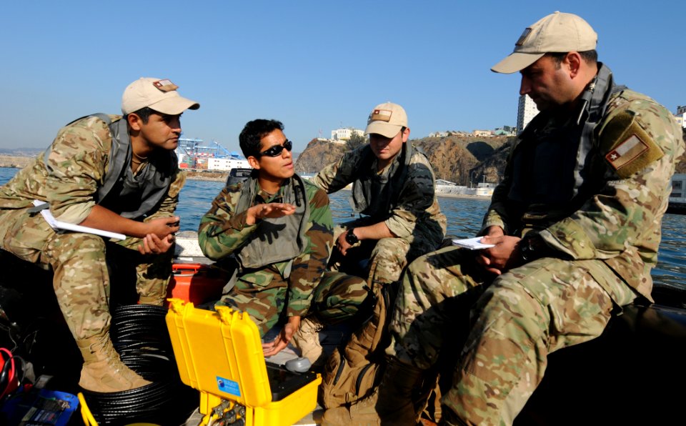 US Navy 110622-N-XD935-147 Navy Diver 1st Class Jimmy Sotelo, center, explains the operation of the Centurion side-scan sonar to Lt. Javier Amor A