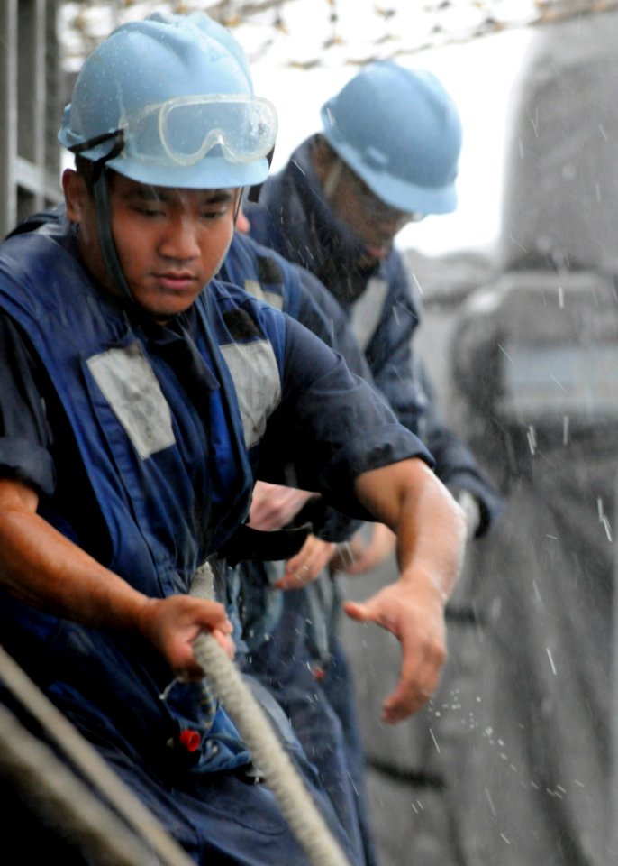 US Navy 110618-N-KB052-064 Seaman Bernard Tanghal, from Guam, heaves in on a line aboard the Ticonderoga-class guided-missile cruiser USS Cowpens (