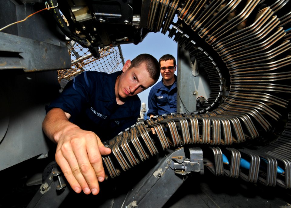 US Navy 110618-N-YM590-079 Gunner's Mate Seaman Ryan Synowietz performs maintenance on a MK-38 25mm gun system aboard the guided-missile cruiser US