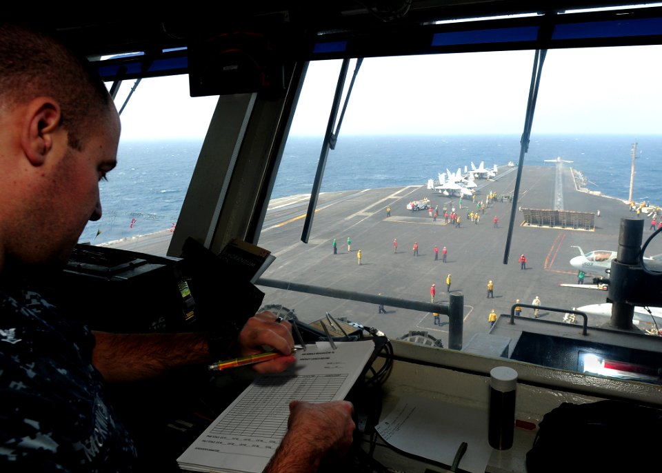 US Navy 110621-N-SB672-029 Aviation Boatswain's Mate (Handling) 3rd Class Travis McKnight checks his watch while logging aircraft launch times from