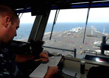 US Navy 110621-N-SB672-029 Aviation Boatswain's Mate (Handling) 3rd Class Travis McKnight checks his watch while logging aircraft launch times from