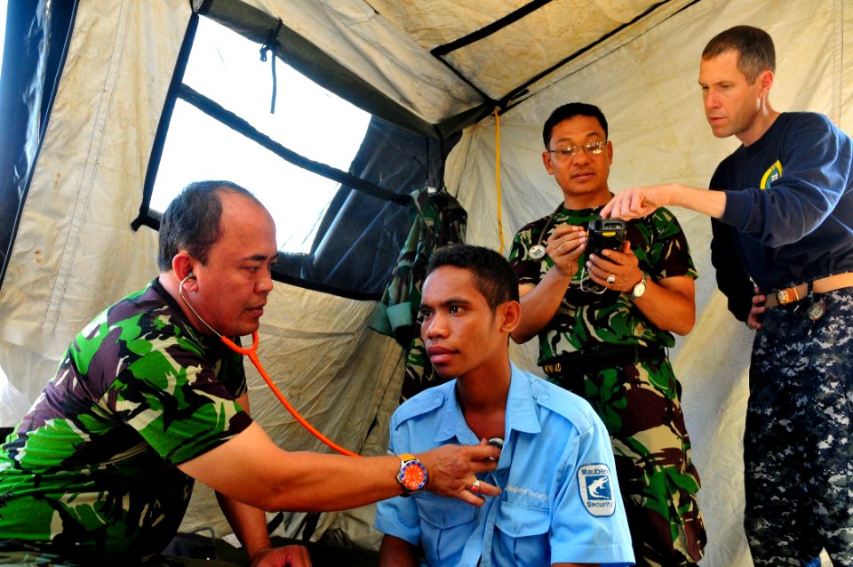 US Navy 110619-N-ZZ999-011 Maj. I Gede Putu Arsana, from the Indonesia army, examines a patient as Lt. Cmdr. Dylan Wessman helps Maj. Faisal Faisal
