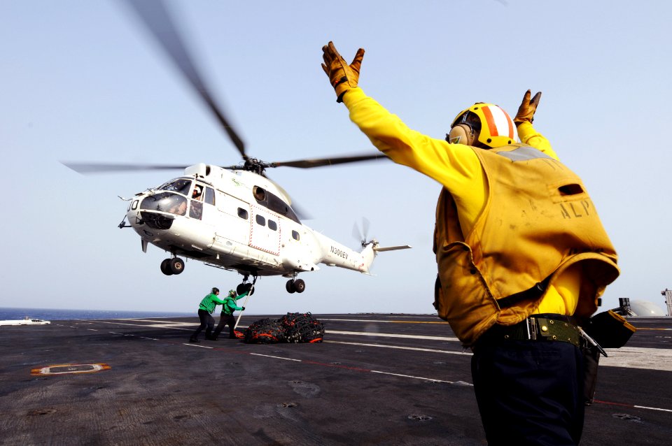 US Navy 110625-N-XE109-350 Aviation Boatswain's Mate (Handling) 1st Class Jerome Gaynor signals a 330J Puma helicopter as Sailors attach cargo nets
