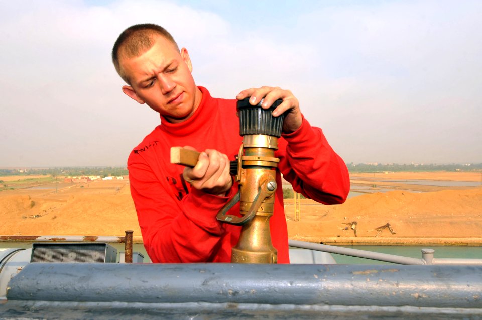 US Navy 110624-N-CH661-019 Aviation Boatswain's Mate (Handling) Airman Travis M. Davis performs corrosion prevention maintenance on a fire hose noz