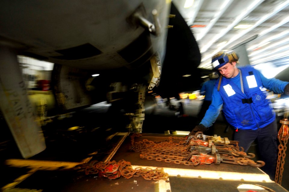 US Navy 110625-N-EE987-010 Aviation Boatswain's Mate Airman Justin Martin prepares chalking chains while moving an F-A-18E Super Hornet