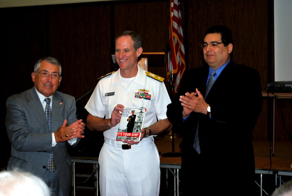 US Navy 110622-N-CI293-058 Rear Adm. Tilghman D. Payne, commander of Navy Region Midwest, receives a book from Bob Ontiveros, left, and Alfred Rami