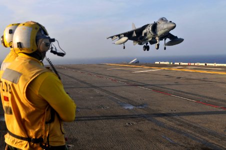 US Navy 110622-N-ZZ999-020 Aviation Boatswain's Mate 2nd Class (Handling) Manuel Arias watches as an AV-8B Harrier from Marine Attack Squadron (VM