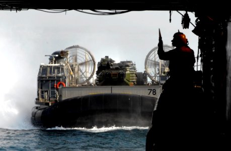 US Navy 110627-N-GH121-178 Boatswain's Mate 3rd Class Ronnie Guerra signals to operators aboard a landing craft air cushion (LCAC) as it enters the