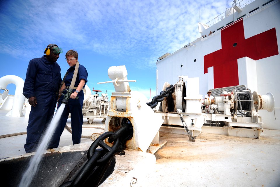 US Navy 110627-N-NY820-071 Civil service mariner Able Seaman Erwin Joiner and Lt. Erinn Gelakoska clean debris from the anchor chain as it is hoist