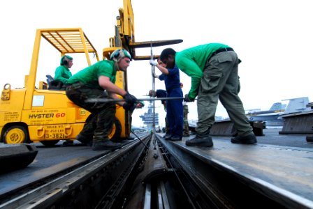 US Navy 110626-N-AW206-005 Aviation Boatswain's Mate (Equipment) Airmen Matthew Sims, left, and Kevin Graves replace sealing strips on one of the c