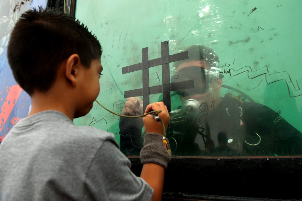 US Navy 110624-N-BT887-153 Explosive Ordnance Disposal Technician 3rd Class Michael Dejesus plays tic-tac-toe with a child