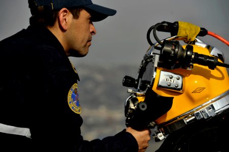 US Navy 110629-N-KB666-030 etty Officer 2nd Class Rodrigo Fuentas, right, prepares for a dive with Mobile Diving and Salvage Unit (MDSU) 2 during a