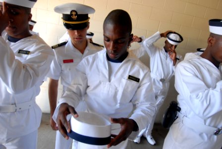 US Navy 110629-N-OA833-004 A plebe in the U.S. Naval Academy Class of 2015 is shown the proper way to wear a Plebe cover while reporting to the sch