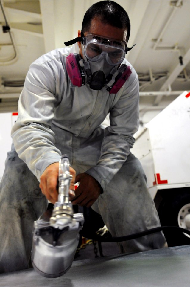 US Navy 110625-N-XE109-553 Aviation Support Equipment Technician 2nd Class Vincente Castillo spray paints the hood of a tractor aboard USS George H