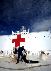 US Navy 110627-N-NY820-010 Civil service mariner Able Seaman Erwin Joiner cleans debris from the anchor chain as it is hoisted aboard the Military