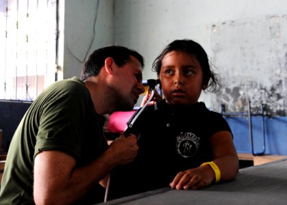 US Navy 110630-F-ET173-099 Peruvian navy Cmdr. Mauricio Adrian checks a patient's ears at the Los Angeles surgical screening site photo