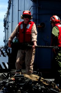 US Navy 110629-N-WA347-295 Cpl. Jason Kay moves .50-caliber machine guns on the flight deck of the forward-deployed amphibious assault ship USS Ess