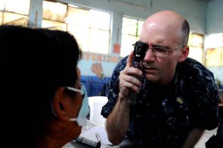 US Navy 110630-F-ET173-122 Capt. William Sray checks a patient's eyes during an exam at the Los Angeles surgical screening site photo