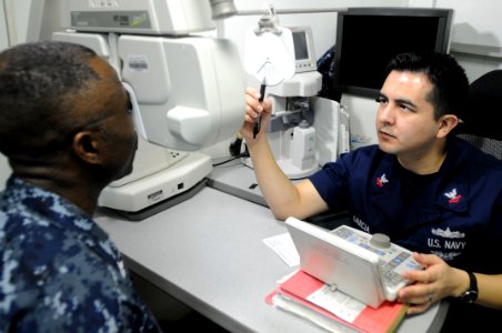 US Navy 110702-N-NB544-021 Hospital Corpsman 2nd Class Luis Garcia, from Phoenix, conducts an eye exam aboard the aircraft carrier USS Ronald Reaga photo