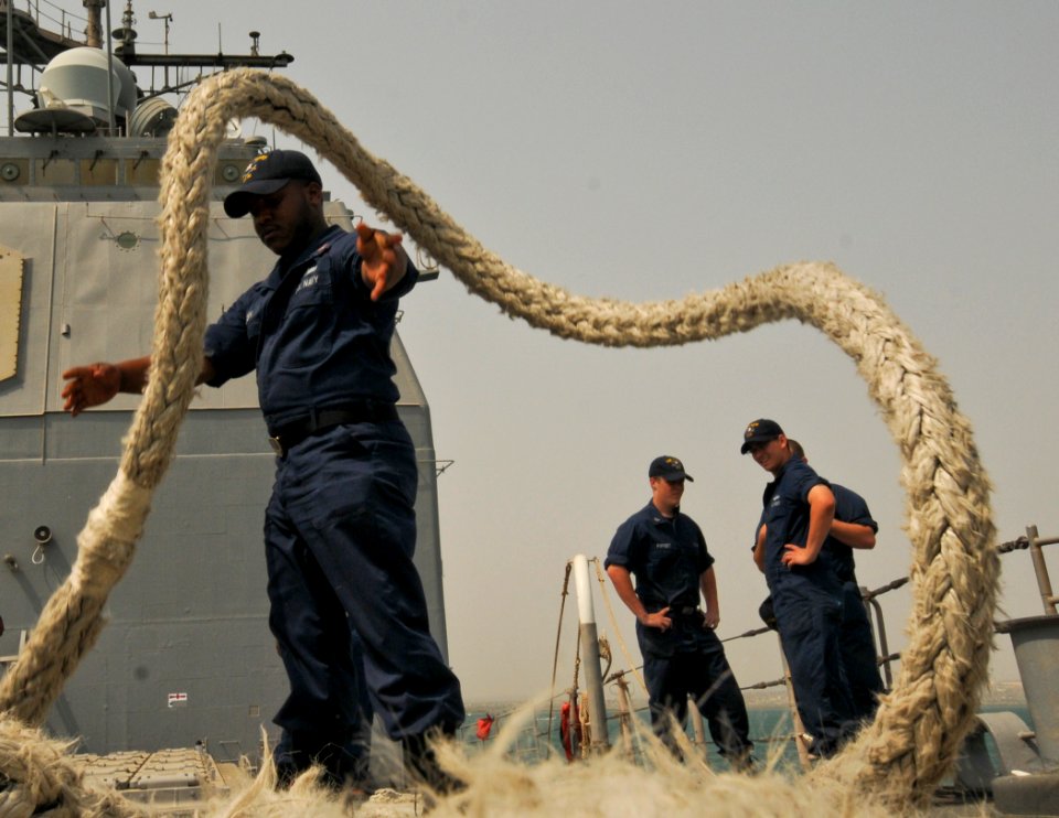US Navy 110701-N-YM590-028 Cryptologic Technician (Technical) 2nd Class Darius Allison, left, tosses a mooring line onto the deck of the guided-mis