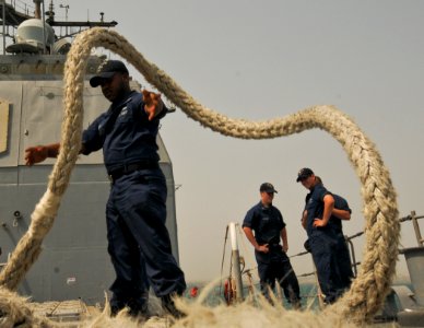 US Navy 110701-N-YM590-028 Cryptologic Technician (Technical) 2nd Class Darius Allison, left, tosses a mooring line onto the deck of the guided-mis photo