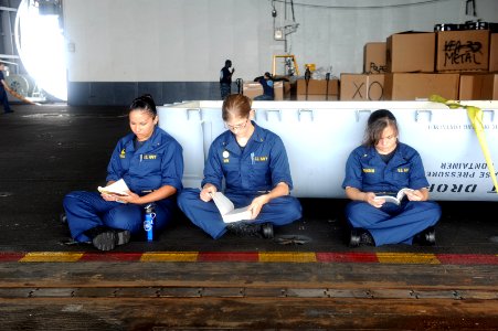 US Navy 110705-N-AU622-004 Midshipmen take a few minutes during their lunch break to read in the hangar bay of the aircraft carrier USS Dwight D. E