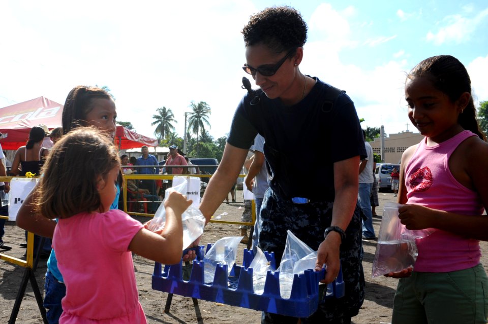 US Navy 110706-F-CF975-005 Yeoman 1st Class Tonya Goff, from Hampton, Va., gives water to local children outside of the Los Angeles medical site in