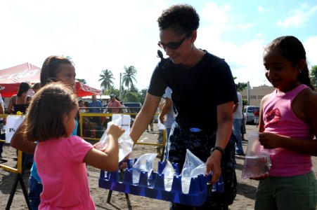 US Navy 110706-F-CF975-005 Yeoman 1st Class Tonya Goff, from Hampton, Va., gives water to local children outside of the Los Angeles medical site in photo