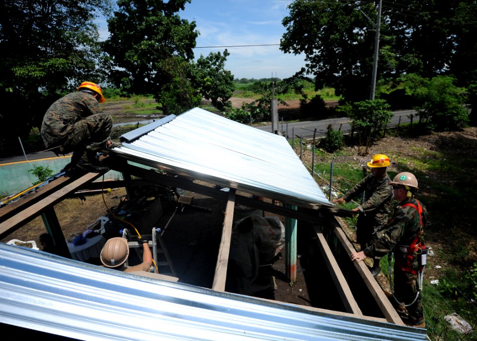 US Navy 110707-N-NY820-258 Construction Electrician 2nd Class Michael Caturegli, right, replaces a tin roof at Escuela Aldea Los Maguelles in Puert