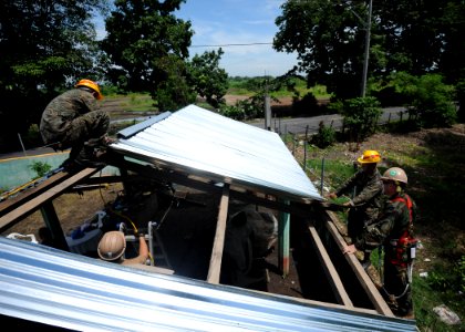 US Navy 110707-N-NY820-258 Construction Electrician 2nd Class Michael Caturegli, right, replaces a tin roof at Escuela Aldea Los Maguelles in Puert