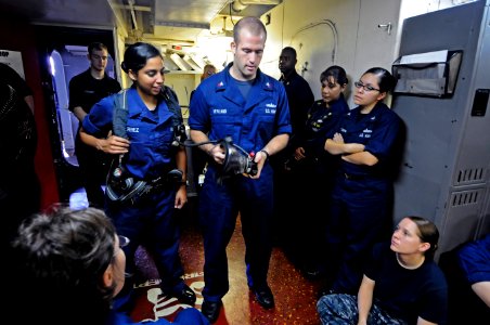 US Navy 110711-N-RC734-017 Damage Controlman 2nd Class Doug Newland, center, trains Sailors how to properly operate a self-contained breathing appa