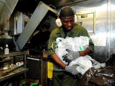US Navy 110712-N-TB177-117 Logistics Specialist 3rd Class Mohammed Yakubu processes plastic in the trash room aboard the guided-missile destroyer U