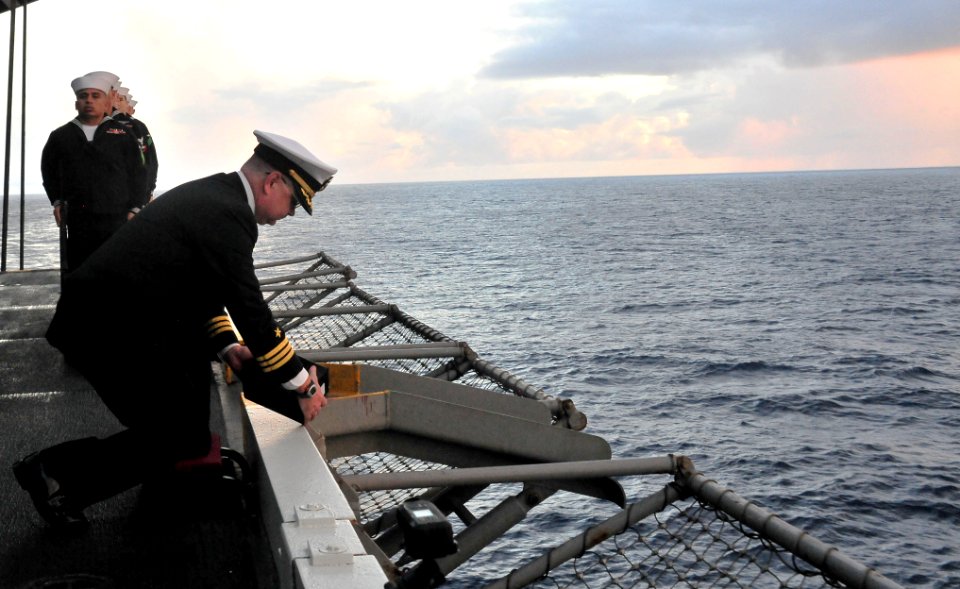 US Navy 110710-N-OP638-036 Cmdr. Todd Mullis pours ashes over the side of the ship during a burial at sea ceremony aboard USS Enterprise (CVN 65)