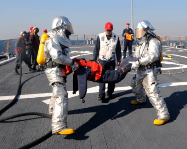 US Navy 110713-N-IO627-003 Sailors in fire protection suits move a mannequin to safety during a flight deck fire drill aboard the guided-missile de