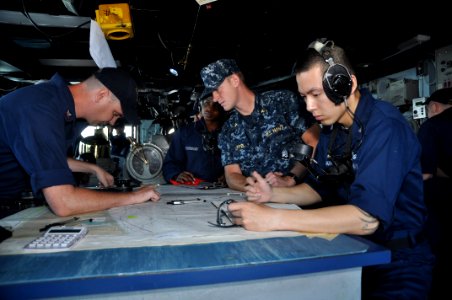 US Navy 110711-N-YX169-063 Midshipman 1st Class Paul Luffel, center, examines a navigation chart as Sailors man the chart table