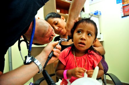 US Navy 110712-N-ZZ999-018 Lt. Cmdr. Cory Russell examines the ear canal of a Micronesian girl photo