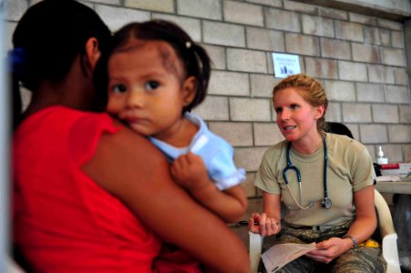 US Navy 110715-F-NJ219-161 Air Force Capt. Kristine Andrews, a pediatrician from Montgomery, Ala., explains common flu symptoms to a patient's moth photo