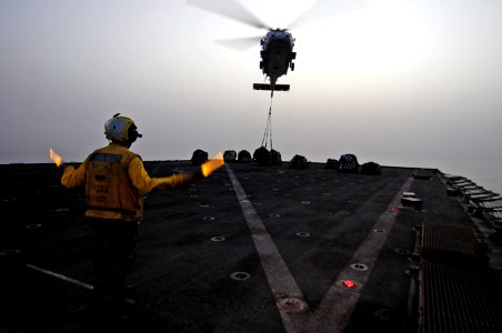 US Navy 110717-N-RC734-322 Boatswain's Mate 2nd Class Randy Buono signals an MH-60S Sea Hawk helicopter during a vertical replenishment