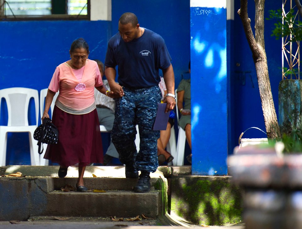 US Navy 110714-N-RM525-163 Hospitalman Ewan Richards, from New York, escorts an elderly woman to the next medical station during a Continuing Promi